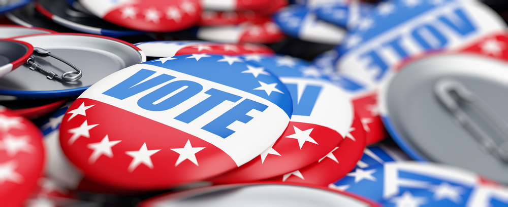 A pile of red, white, and blue buttons that say vote