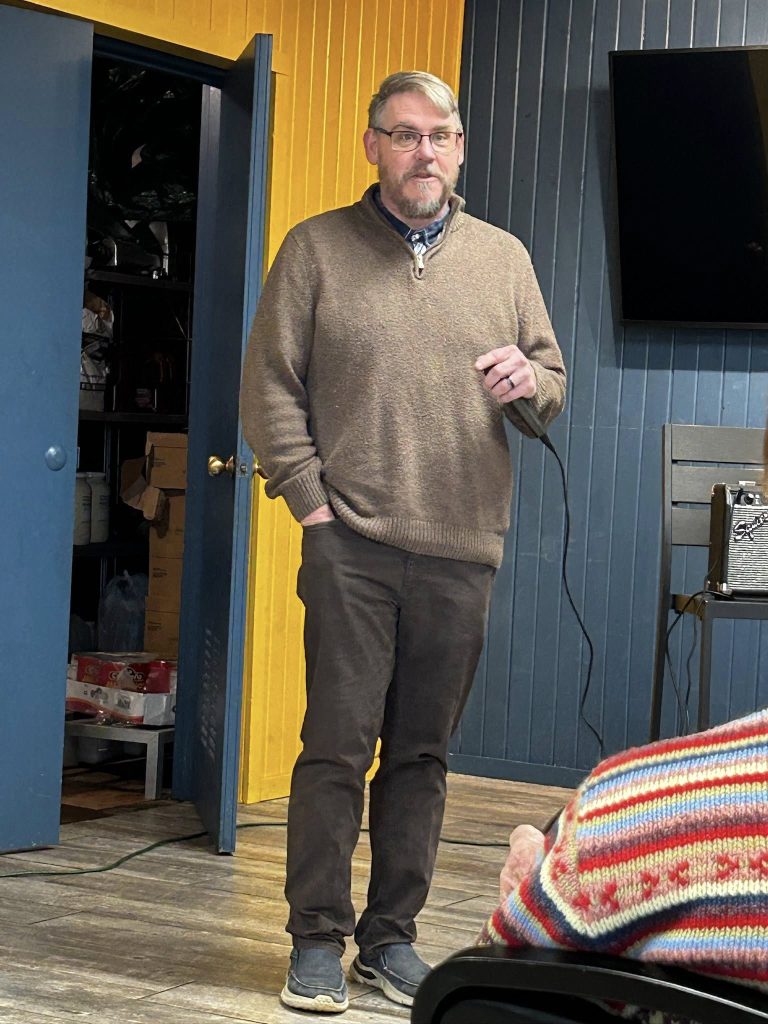 Brian Shaver stands in front and addresses the crowd.