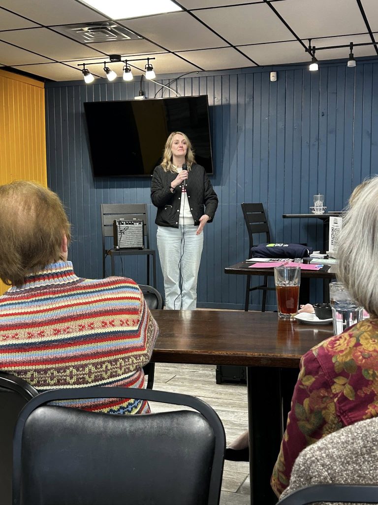Gina Grandillo stands in front and addresses the group.